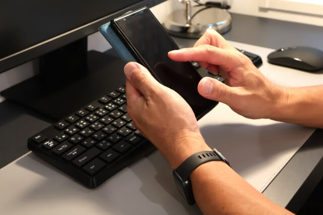 デスクでスマホ操作する手元