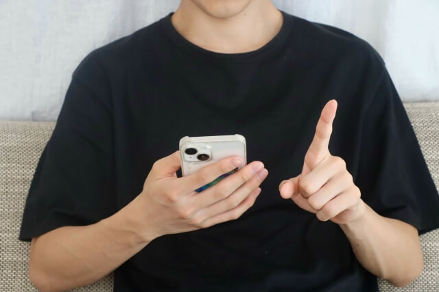 スマートフォンを指差す黒いシャツの男性