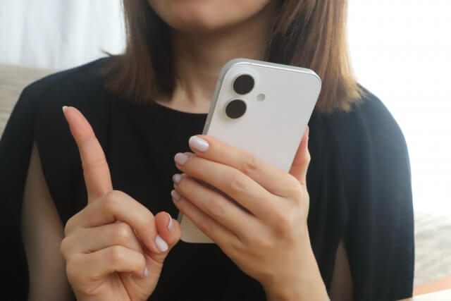 スマホを持つ女性と指差す手