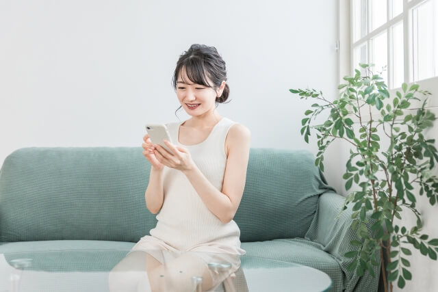 リビングでくつろぐスマホ女性