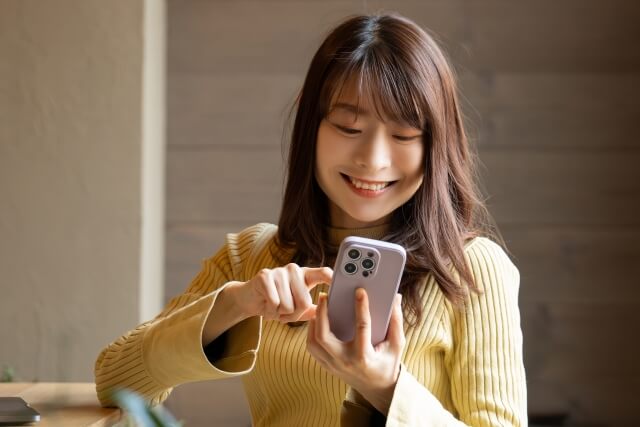 スマホで笑顔を見せる女性
